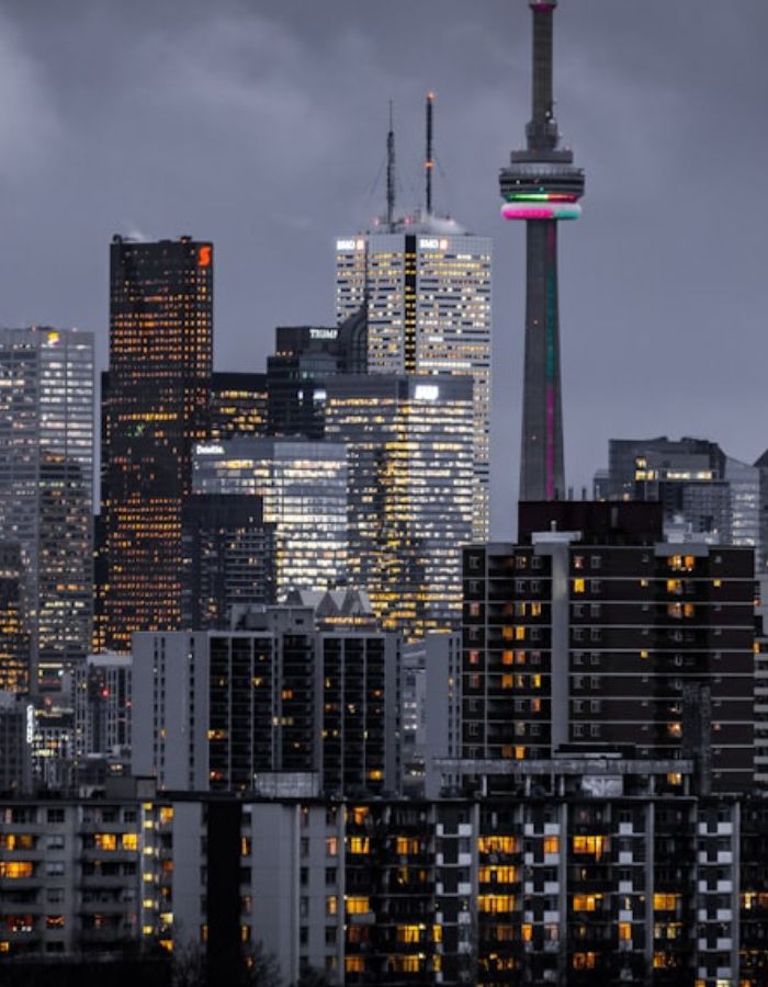 Vista noturna do skyline de uma metrópole com prédios residenciais e comerciais iluminados, arranha-céus ao fundo, fotografia realista de construção imobiliária urbana